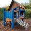 Olle's Playhouse wooden playhouse with a slide for children in a park.