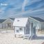 Olle's Playhouse in a sandy playground with modern houses in the background.