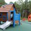 Wooden playhouse with blue accents and slide in a playground titled Olle's Playhouse.